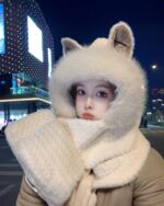 Woman wearing a fluffy fox ears scarf and hooded winter hat at night.
