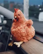 A plush fat chicken toy, soft and cuddly, resting on a wooden surface.