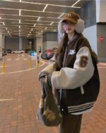 Woman wearing a brown and white korean aesthetic jacket with varsity details.