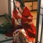 A woman wearing a vibrant red aesthetic kimono in a traditional Japanese setting.