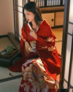 A woman wearing a vibrant red aesthetic kimono in a traditional Japanese setting.
