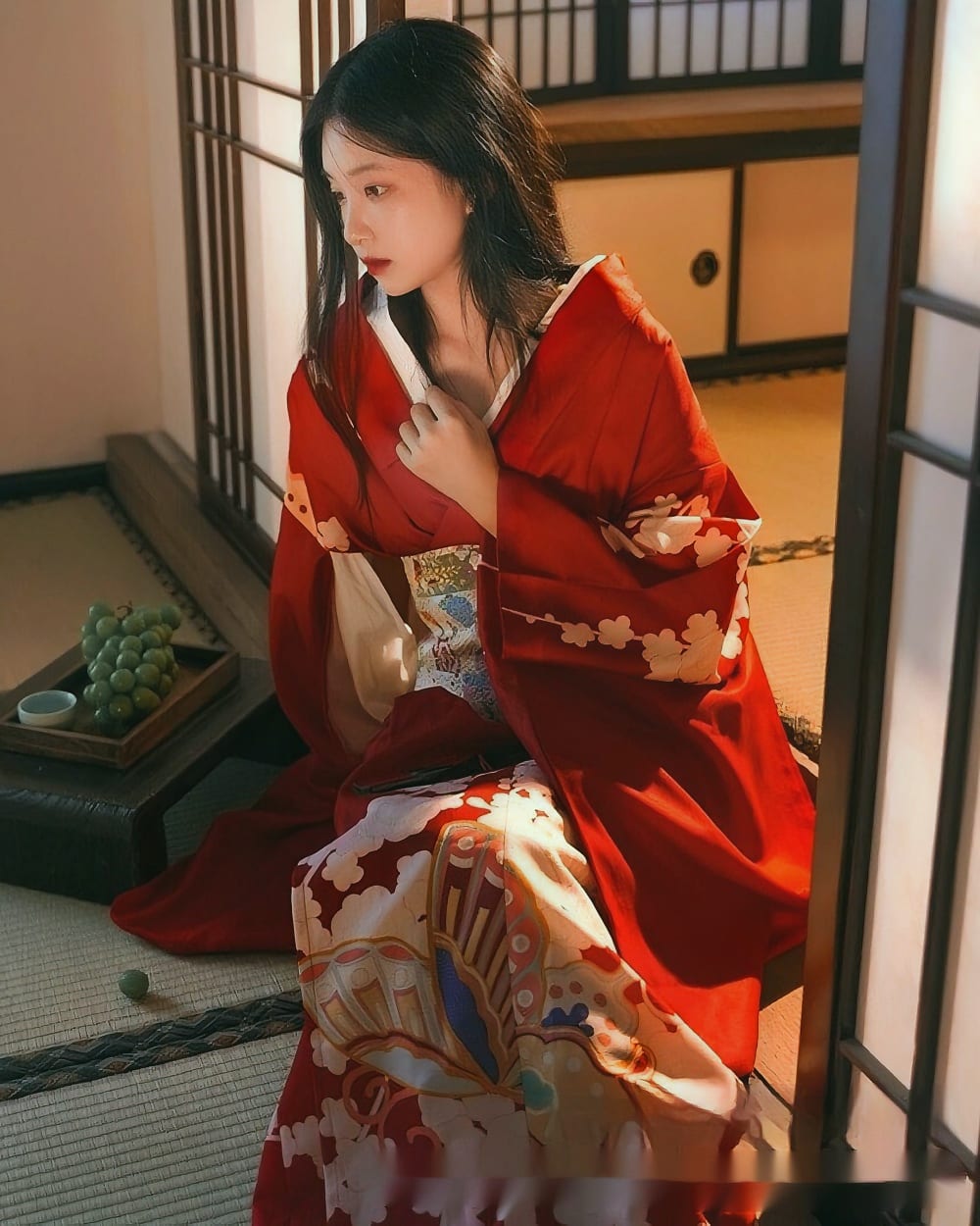 A woman wearing a vibrant red aesthetic kimono in a traditional Japanese setting.