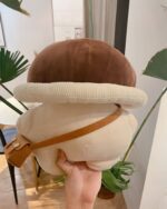 Close-up of a brown mushroom homunculus plushie with a corduroy collar and strap.