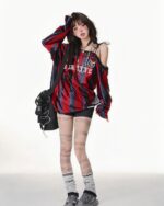 Off shoulder coquette aesthetic sweatshirt worn by a model, featuring a red and black striped design.