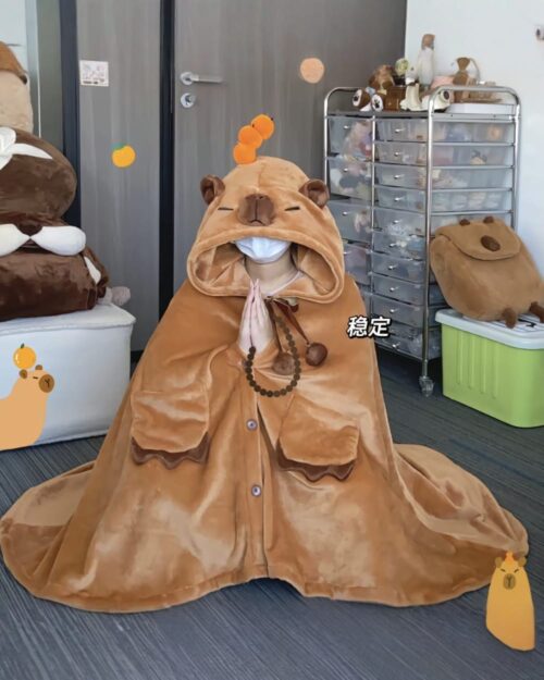 A brown capybara cloak is worn by a person with stuffed animals, showcasing the Kawaii Clothes product.