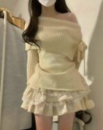 Cream-colored one-shoulder knitwear sweater paired with a ruffled skirt.