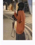 Woman wearing a brown Korean aesthetic sweater outdoors at night.