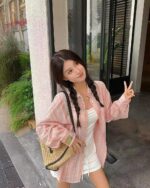 Woman wearing a pink and white long-sleeved striped korean aesthetic shirt outdoors.