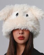 A fluffy eyed hat with plush white fur and large black eyes on a woman's head.