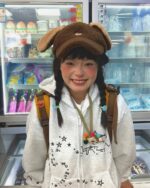 Model wearing a y2k kaomoji hoodie with a bear beanie and backpack.