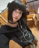 Person wearing a grunge aesthetic sweater with off-shoulder detail and black hair.