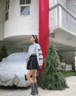 Gray bowed pullover sweater with bow details worn by a model outdoors.