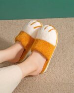 Close-up of yellow and white cat paw slippers on a rug.
