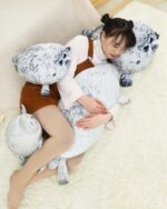 Two Yuki the Seal Plush toys and a person cuddling with them on a rug.