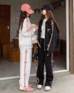Two women wearing a korean aesthetic set - white and black zip-up jacket and pants, pink accents.