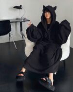 Woman wearing black little devil pajamas with hood and fluffy slippers, loungewear outfit.