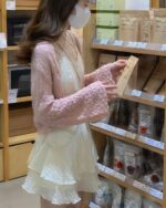 Woman wearing a lolita french dress, a layered lace top, and a knitted shawl in a supermarket setting.