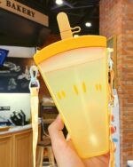 Close-up of a yellow kawaii fruit bottle shaped like a popsicle, featuring a handle and decorative pattern.