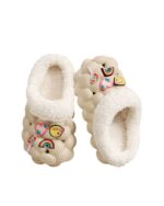 Pair of beige fluffy foam slippers with attached decorative charms.