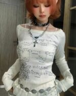 White coquette long sleeve top with musical notes print, off-the-shoulder style.
