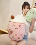 Two bubble tea plushies – pink and green – are held by a woman. Product: bubble tea plushies.