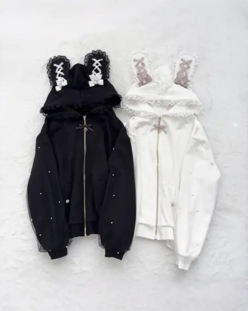 Two rabbit eared cardigan hoodies, one black and one white, with lace trim and decorative accents.