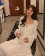 Woman wearing a white soft girl aesthetic nightdress, holding a mug.