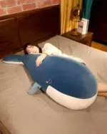 Blue kawaii whale plushie resting on a bed, soft and cuddly.