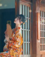 Woman wearing a flower summer yukata against a wooden door.