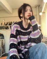 Close-up of a black and purple y2k striped sweater with a chunky knit texture.