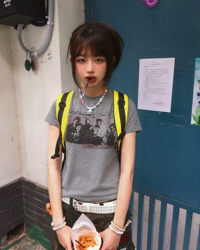Person wearing a retro grunge t-shirt with a band graphic, backpack, and accessories.