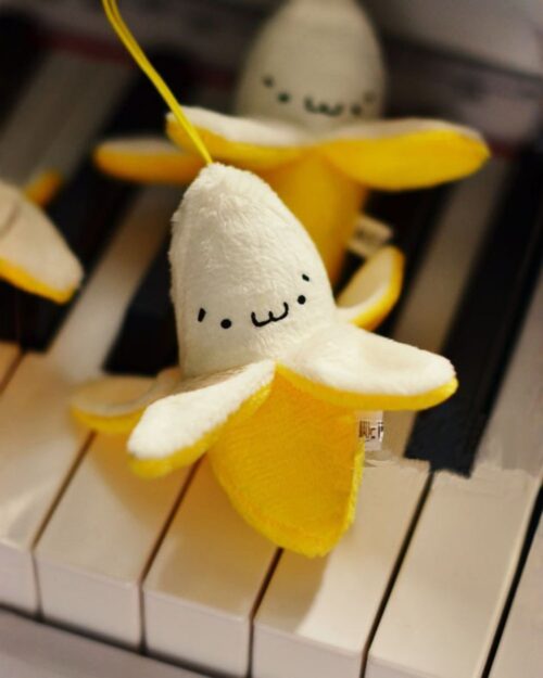 Cute chibi banana plushie with a yellow peel and small eyes, kawaii fruit keychain.
