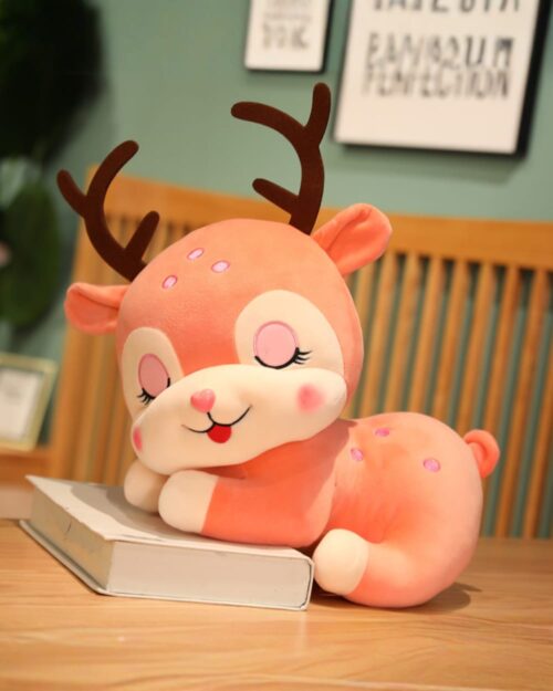 Pink baby deer plushie resting on a table with eyes closed.