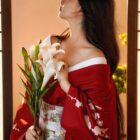 Woman wearing a red aesthetic kimono with white flowers, standing in a traditional Japanese setting.