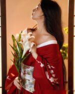 Woman wearing a red aesthetic kimono with white flowers, standing in a traditional Japanese setting.