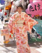A woman wearing a pink japanese yukata with floral pattern in a Japanese street.