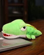 Kawaii animal puppets plushie of a green crocodile, resting on a laptop.