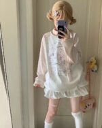 A person wearing a pink Nyanko t-shirt with a cute cartoon design, part of a cutecore aesthetic outfit.