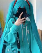 Close-up of a turquoise harajuku hoodie worn by a person with blue hair and accessories.