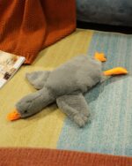 Soft gray giant goose plush toy lying on a colorful rug.