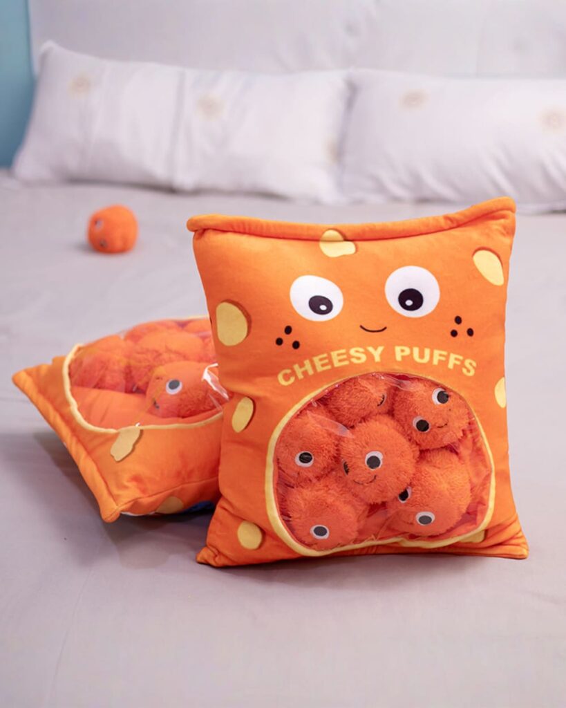 Two Cheesy Puffs plushies, resembling snack bags, on a bed.