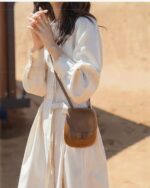 Woman wearing a beige korean style dress with long sleeves and a belt.