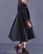 Black long hooded coat with a detachable hood and layered fabric.