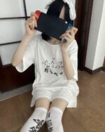 Person wearing a kawaii loose t-shirt and matching shorts while playing a Nintendo Switch.