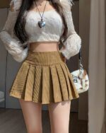 Brown preppy corduroy skirt with pleats, paired with a sweater and bag.