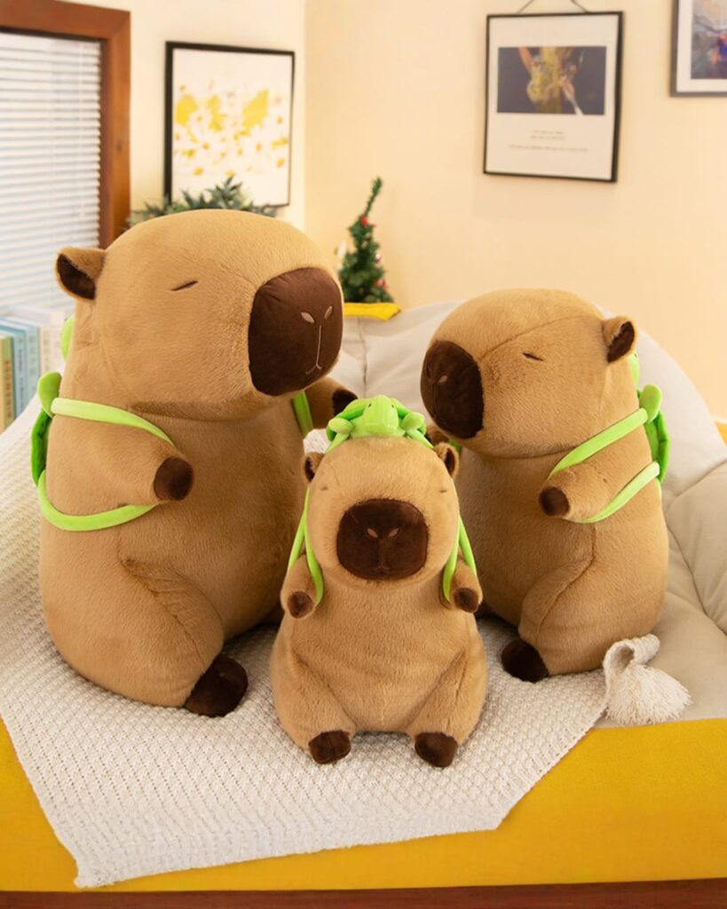 Backpack Cabypara - Turtle Collection plush capybara sitting on a yellow blanket.