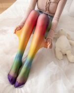 A pair of japanese rainbow socks, featuring a colorful gradient design, displayed on a bed.