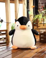 A black chonky penguin plushie, soft and cuddly, displayed indoors.