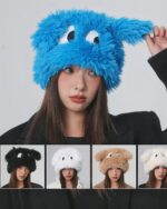 A fluffy eyed hat in blue, alongside other colored fluffy eyed hats.