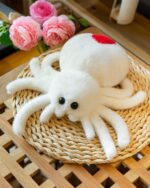 White spooky cute spider plush toy on a woven tray.